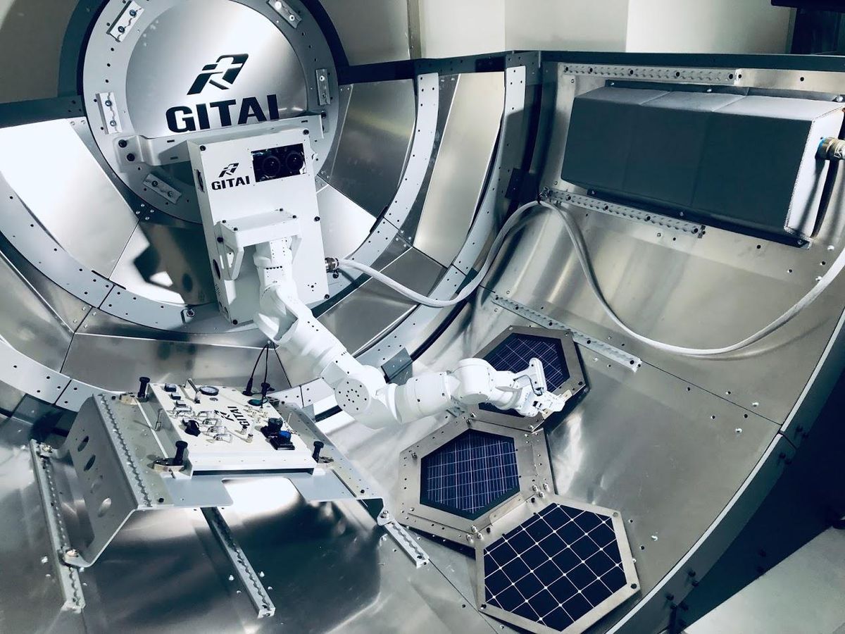 一个白色的机械臂在国际空间站气闸的测试模型内组装六角形太阳能电池板
