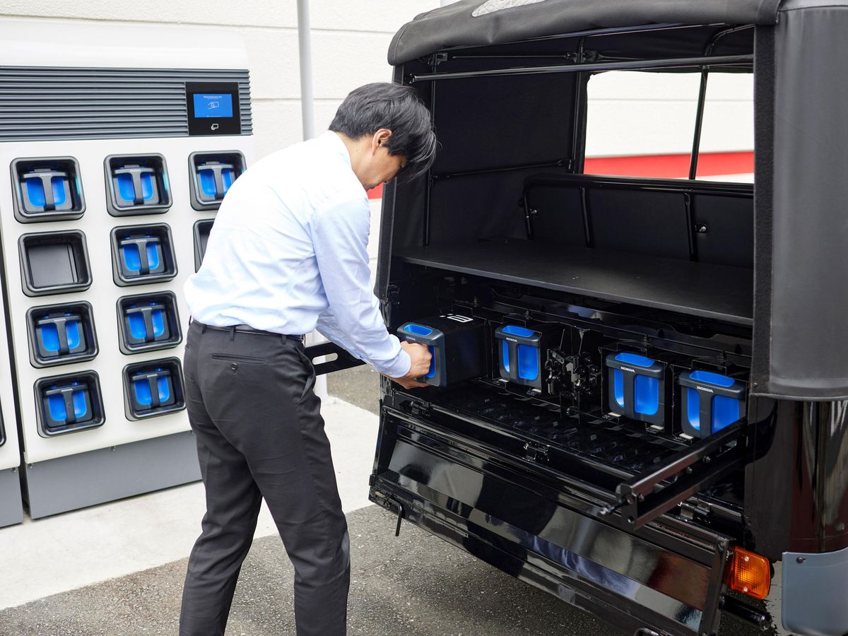 本田研究人员将充电的移动电源组电子电池插入电动人力车。
